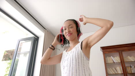Biracial-young-woman-dancing-alone-in-room-at-home