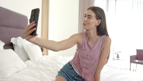 Teenage-Caucasian-girl-takes-a-selfie,-winking-playfully-at-her-phone-at-home