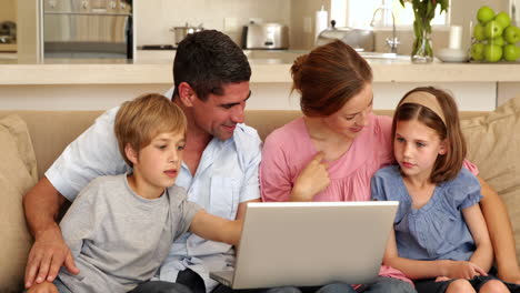 Familia-Feliz-Sentada-En-El-Sofá-Usando-Una-Computadora-Portátil