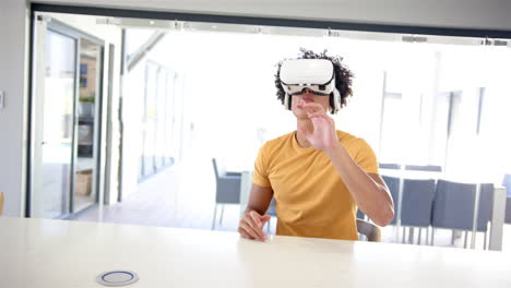 A-young-biracial-man-is-using-virtual-reality-goggles-at-home-in-the-kitchen,-white-background