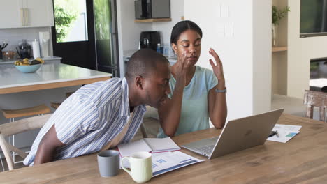 A-diverse-couple-is-managing-finances-at-home-using-a-laptop