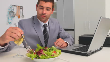 Businessman-working-on-his-laptop-while-he-is-eating-