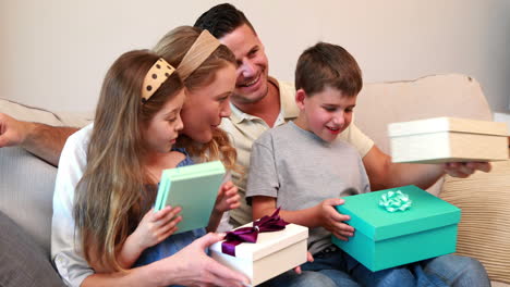 Happy-young-family-sitting-on-sofa-with-birthday-presents