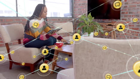 Animation-of-network-of-connections-with-icons-over-biracial-casual-businesswoman-using-tablet