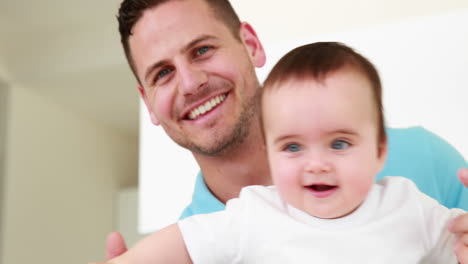 Smiling-father-helping-his-baby-boy-stand-up