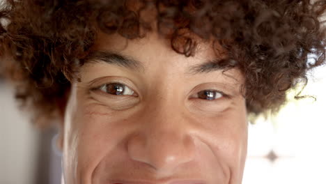 A-close-up-captures-a-young-biracial-man-with-a-cheerful-expression-at-home
