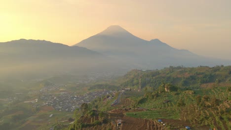 Mountain-Sindoro-during-golden-sunset-in-Indonesia,-aerial-establisher