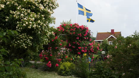 Bandera-Sueca,-Casa-Roja-Y-Flores-En-Una-Idílica-Escena-Rural-De-Verano