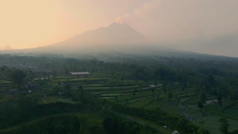 Adelante-Aéreo-Sobre-La-Campiña-Indonesia-De-Java-Con-El-Volcán-Merapi-En-La-Distancia