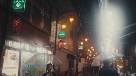 Gente-Con-Paraguas-En-La-Ciudad-Húmeda-Y-Lluviosa-Durante-La-Noche-En-Osaka,-Japón