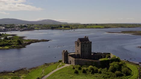 órbita-Aérea-Del-Castillo-De-Dunguaire,-La-Toma-Revela-La-Ciudad-De-Kinvara-Al-Fondo