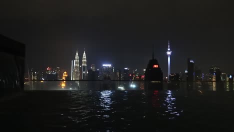 Skyline-Von-Kuala-Lumpur-Bei-Nacht-Vom-Infinity-Pool-Auf-Dem-Dach-Eines-Wolkenkratzers