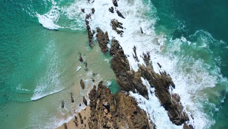 4K-Drone-video-birds-eye-ariel-view-of-the-white-waves-crashing-looking-down-flying-backwards-revealing-the-rock-formations-as-the-waves-crash-around-them