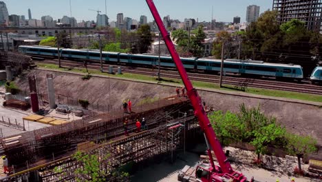 Train-on-tracks-by-construction-site-in-sunny-Buenos-Aires,-aerial-pan