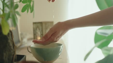 Hands-gently-hover-over-a-bowl-of-water-in-a-peaceful,-sunlit-room