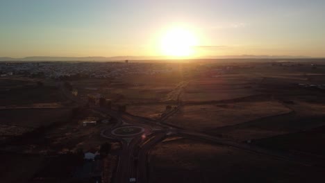 Pozoblanco-town-at-sunrise-with-clear-skies-and-a-visible-roundabout,-aerial-view