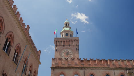 Vista-Soleada-De-Una-Antigua-Torre-En-Bolonia,-Italia,-Con-Banderas-Ondeando