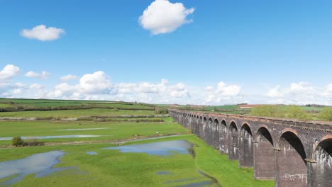 Drone-flight-alongside-historic-Welland-Viaduct-Northamptonshire,-otherwise-know-as-the-Harringworth-and-Seaton-Viaduct-on-sunny-day-showing-whole-expanse-of-England’s-longest-viaduct-and-valley-below