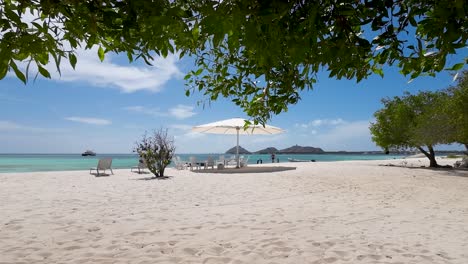 Einsame-Strandszene-Mit-Sonnenschirm-Und-Stühlen-Bereit-Für-Touristen,-Luxusvilla