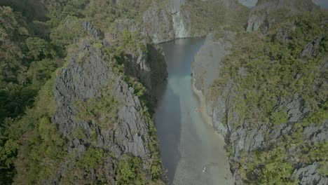 Mountains-and-kayaks-in-calm-water-in-sunny-Philippines,-aerial-pull-out
