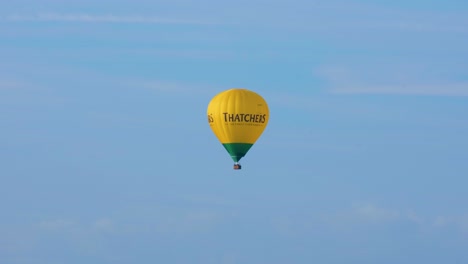 Yellow-Thatchers-Cider-hot-air-balloon-against-blue-sky-flying-over-the-Somerset-Levels