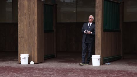 Footage-of-Todd-Pletcher,-a-renowned-horse-trainer,-standing-alone-in-the-paddock-at-Churchill-Downs-before-the-Kentucky-Derby