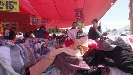 Mujeres-Latinas-Adultas-Comprando-Ropa-De-Segunda-Mano-En-El-Tradicional-Mercadillo-De-La-Zona-Urbana-De-México