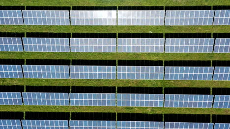 Solar-panels-on-a-green-field-capturing-renewable-energy,-aerial-view