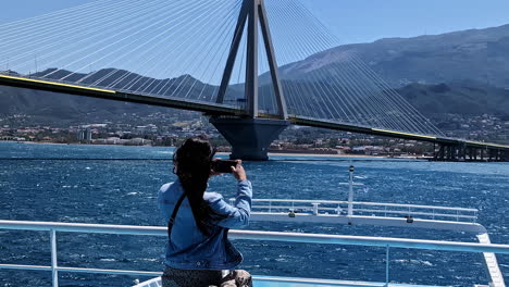 Beautiful-lady-taking-pictures-of-Rio-bridge-from-moving-vessel,-back-view