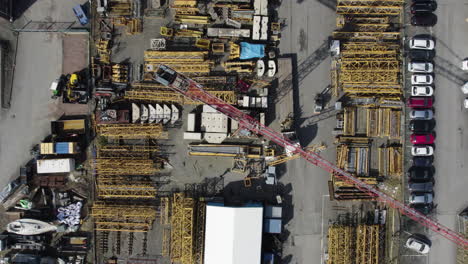 Building-Crane-Loading-at-Outdoor-Construction-Rental-Company,-Aerial-Top-Down