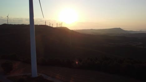 Turbinas-Eólicas-Girando-Al-Atardecer-En-Igualada,-Barcelona-Con-Montañas-Al-Fondo