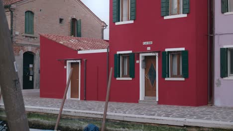Charming-red-house-with-green-shutters-and-canal-view-in-Burano-Island,-Venice