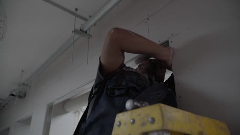 Adult-Latino-man-working-taking-measurements-on-wall-construction-with-drywall