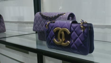 Chanel-Bolsos-De-Lujo-De-Color-Púrpura-Exhibidos-En-Un-Estante-De-Vidrio-En-Una-Boutique-De-Alta-Gama