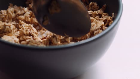 Spoon-Stirring-Almond-and-Raisin-Granola-with-Oat-Milk-in-Slow-Motion