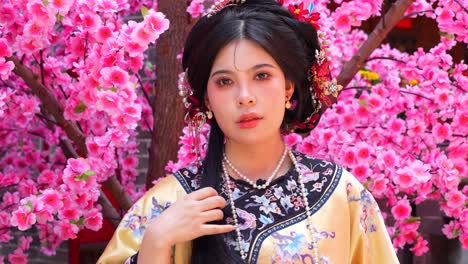 Closeup-of-a-woman-in-traditional-Qing-Dynasty-attire,-set-against-pink-blossoms-in-Pingyao,-China