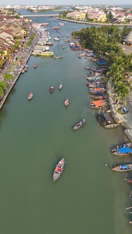Daytime-aerial-over-Hoi-An-River-in-Vietnam-with-boats,-vertical-video