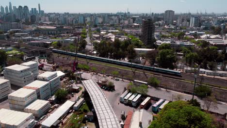 Wide-aerial-of-train-passing-industrial-containers-and-Buenos-Aires-skyline