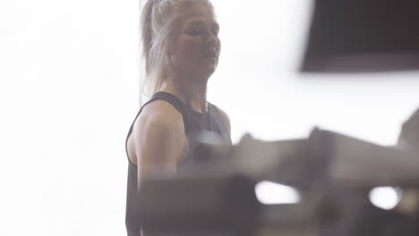 Attractive-Swedish-female-athlete-does-arm-workout-using-weight-plate,-high-key