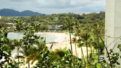 Vista-De-La-Playa-Con-Poca-Gente-En-Kauai-A-Través-De-Palmeras-En-Cámara-Lenta
