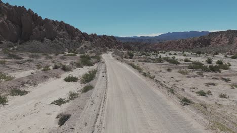 A-van-advancing-along-Ruta-40-on-a-gravel-road-in-the-northern-province-of-Salta,-Argentina