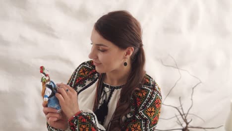 portrait-depicts-a-charming-young-woman-in-embroidered-authentic-Ukrainian-attire-holding-a-handmade-motanka-doll