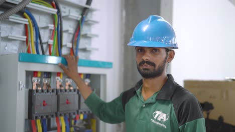 Pakistani-Engineer-Wearing-Blue-Hard-Standing-Beside-Control-Box-At-Factory-Warehouse