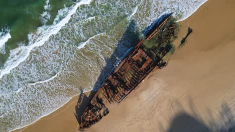 4K-Drone-Ariel-Video-spinning-around-the-Maheno-Shipwreck-by-the-blue-green-ocean-on-the-beach-on-K'Gari-Frasier-Island,-Queensland-Australia