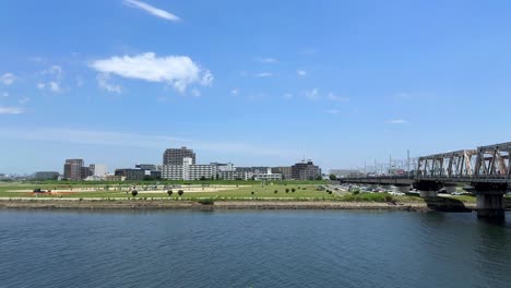 Una-Vista-Panorámica-Del-Horizonte-De-Una-Ciudad-Con-Edificios-Junto-A-Un-Río-Tranquilo-Bajo-Un-Cielo-Azul-Brillante