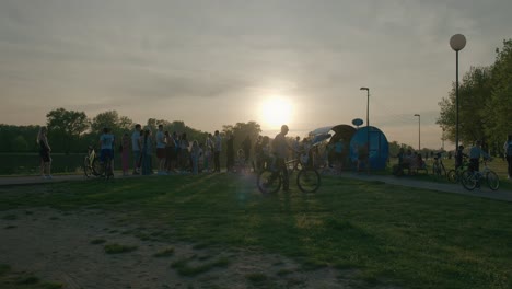 People-biking-and-gathering-at-a-lakeside-kiosk-during-sunset-in-Jarun-Lake,-Zagreb-Croatia