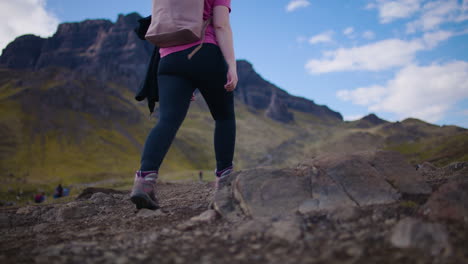 Backpacker-woman-walking-in-Scottish-countryside,-The-Storr-in-background