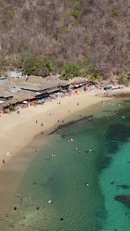 Vertical-aerial-slow-motion-view-of-the-beaches-in-Huatulco,-Oaxaca,-Mexico