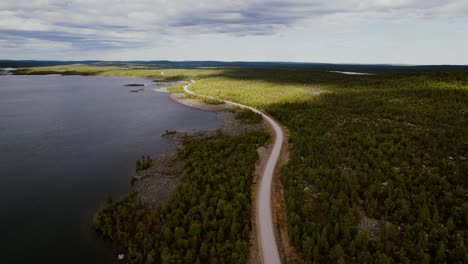 Drone-shot-with-lonely-road-between-the-green-forest-and-calm-lake