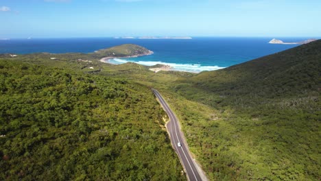 4K-drone-video-following-a-white-camper-van-driving-on-the-road-through-Wilsons-Promontory-in-Victoria,-Australia